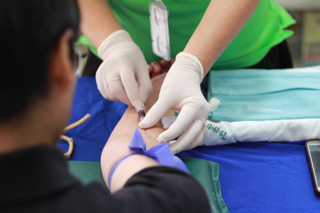 A healthcare professional administering an injection to a patients arm during a medical procedure.